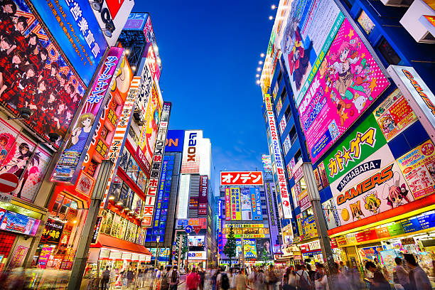 Tokyo, Japan - August 1, 2015: Crowds pass below colorful signs in Akihabara. The well known electronics district specializes in the sales of video games, anime, manga, and computer goods.